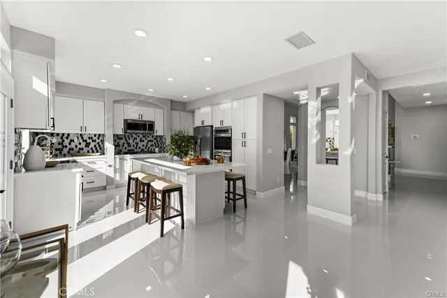 a kitchen with stainless steel appliances kitchen island granite countertop a refrigerator and a dining table