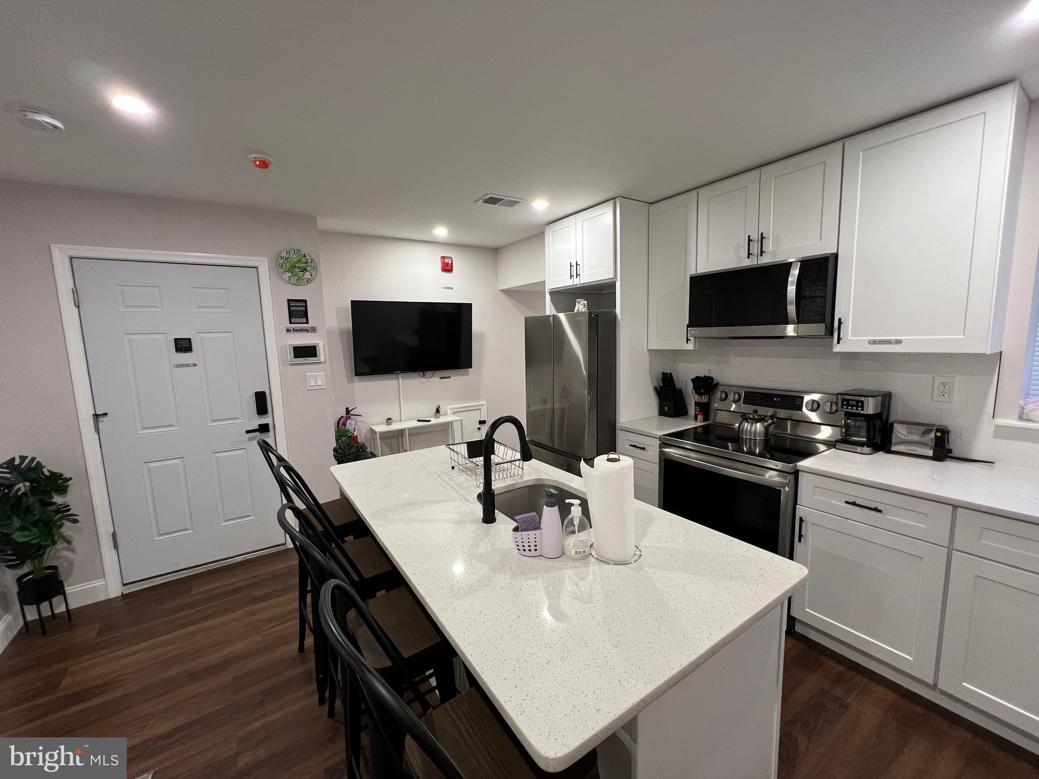 1985 North 63rd Street, Unit 3 Philadelphia, PA 19151 - Photo 2 of 23 a kitchen with a microwave a stove a sink a microwave a dining table and chairs