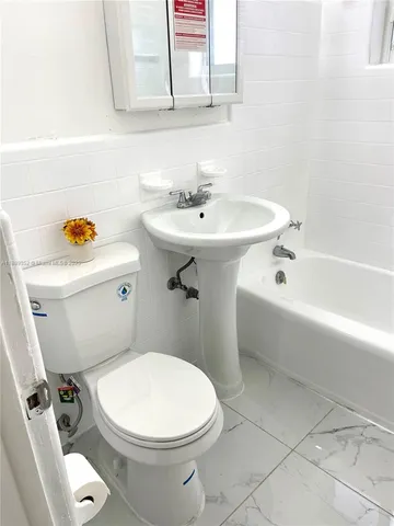 a white toilet sitting next to a white sink and vanity