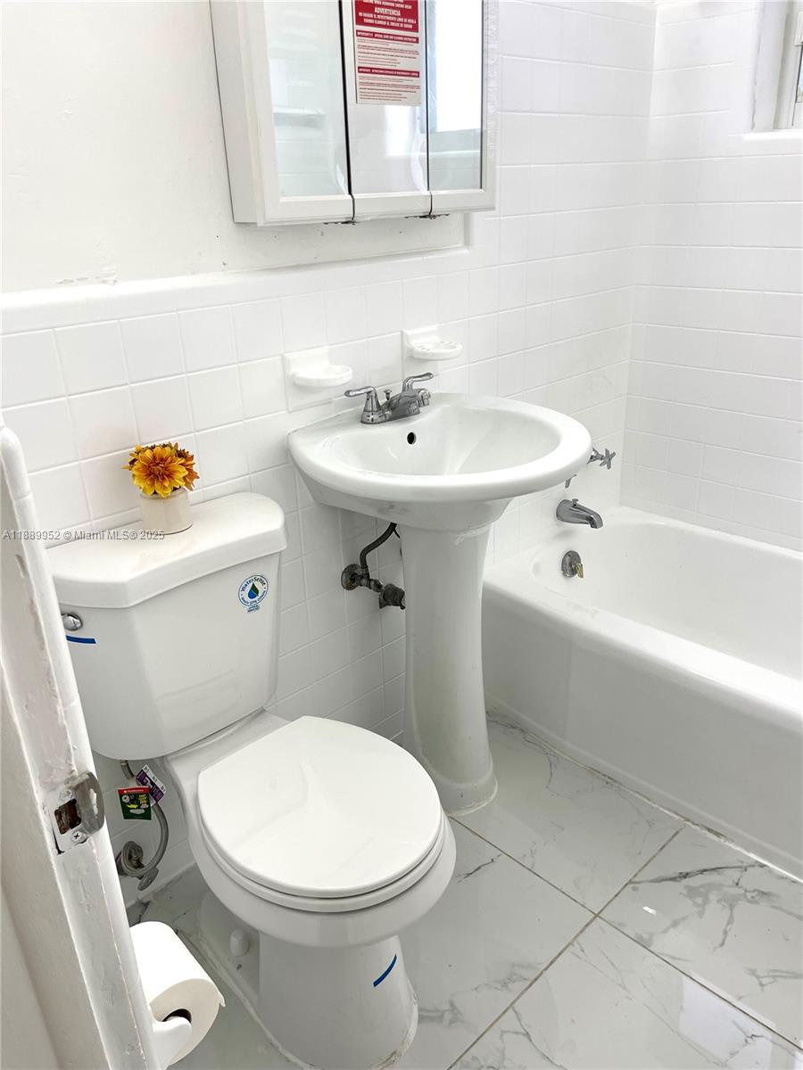 3175 Southwest 27th Terrace, Unit 3175 Miami, FL 33133 - Photo 14 of 17 a white toilet sitting next to a white sink and vanity