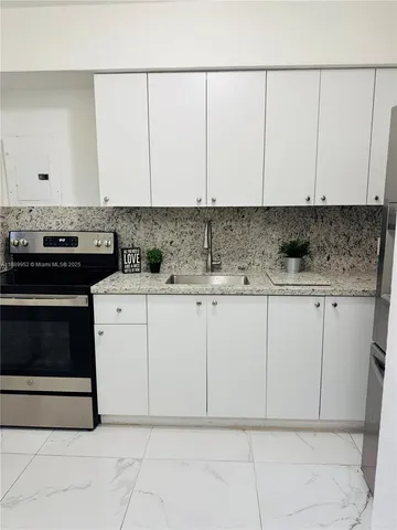 a kitchen with granite countertop white cabinets and white appliances