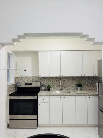 a kitchen with stainless steel appliances granite countertop a stove a sink and a white cabinets