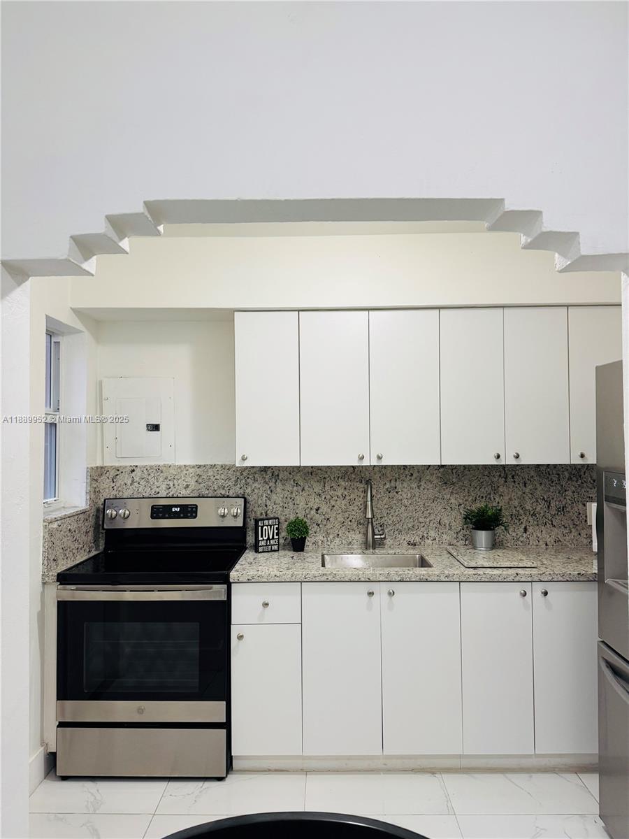 3175 Southwest 27th Terrace, Unit 3175 Miami, FL 33133 - Photo 17 of 17 a kitchen with stainless steel appliances granite countertop a stove a sink and a white cabinets