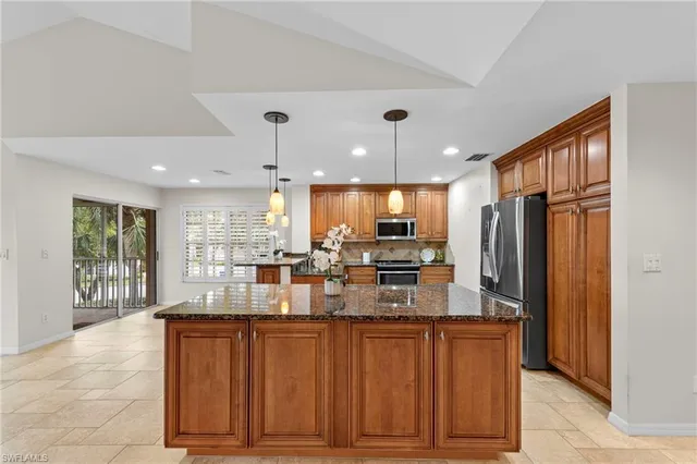 a kitchen with stainless steel appliances granite countertop a refrigerator a sink a dining table and chairs with wooden floor