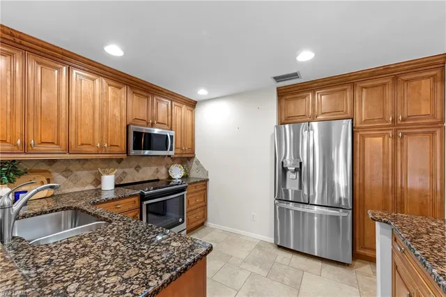 a kitchen with stainless steel appliances granite countertop a refrigerator stove and sink