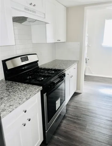a kitchen with granite countertop white cabinets and black appliances