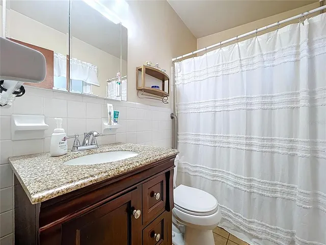a bathroom with a granite countertop sink and a toilet
