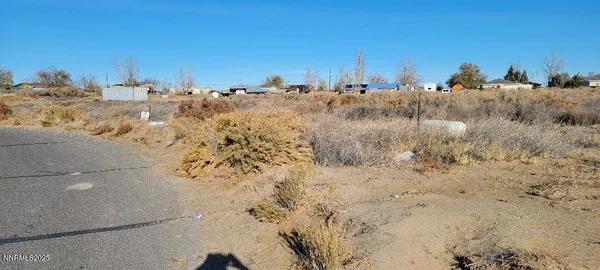 a view of a dry field with a house in the background