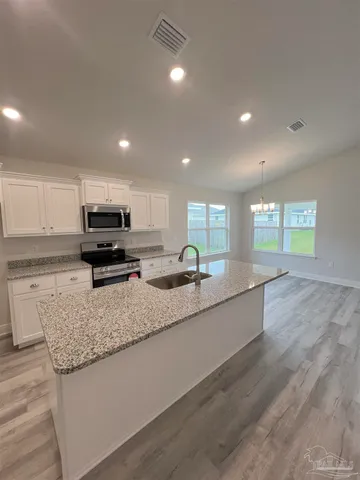 a large kitchen with granite countertop a stove a sink a counter space and cabinets