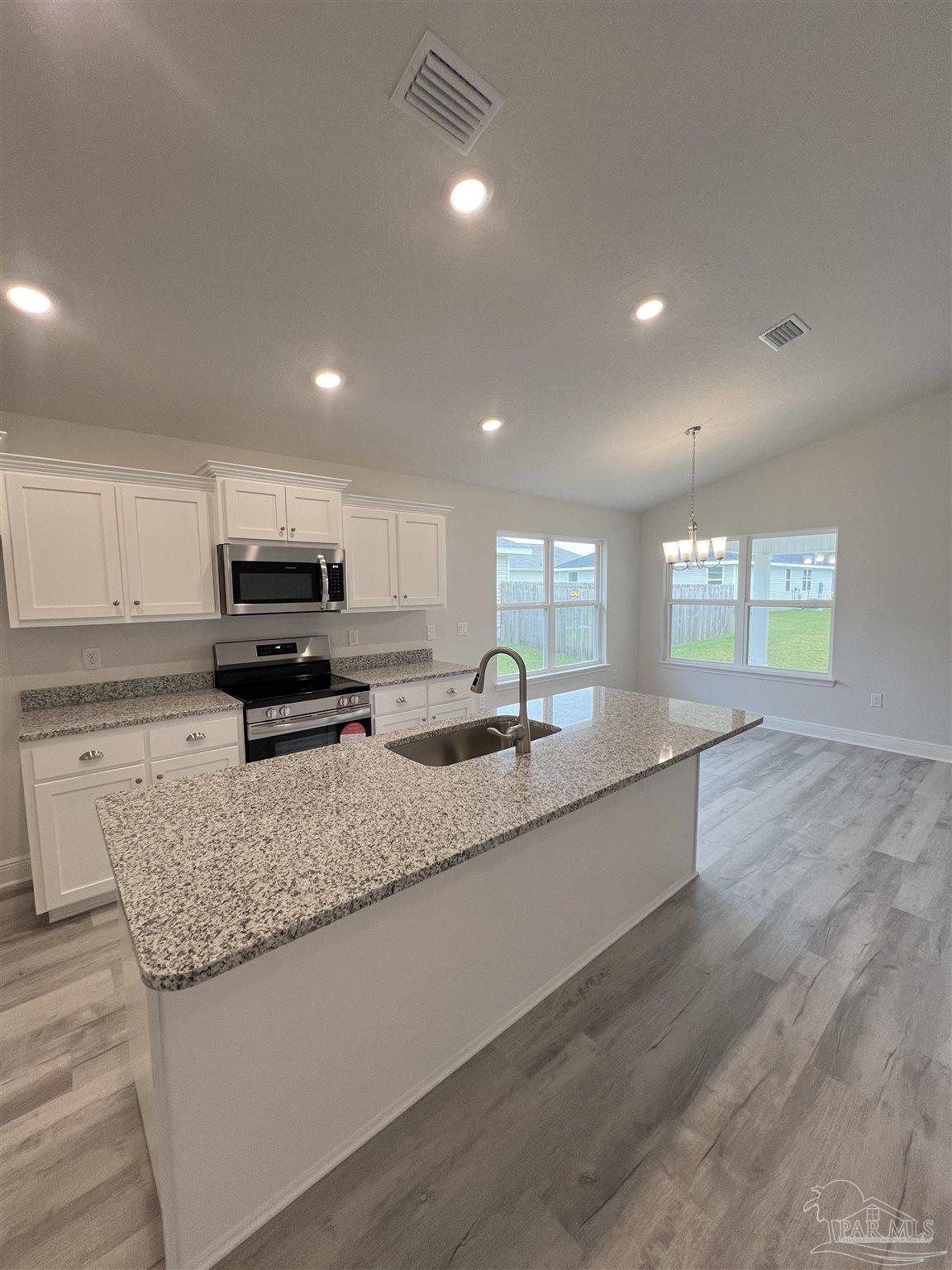 904 Rustling Pine Road, Unit 22B Cantonment, FL 32533 - Photo 3 of 10 a large kitchen with granite countertop a stove a sink a counter space and cabinets