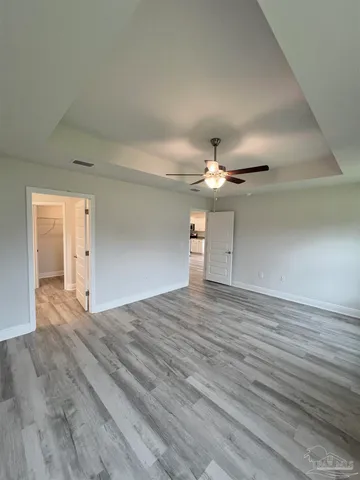 a view of empty room with wooden floor and ceiling fan