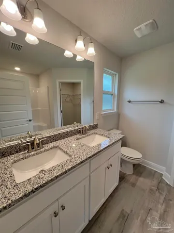 a bathroom with a granite countertop sink a toilet and a mirror