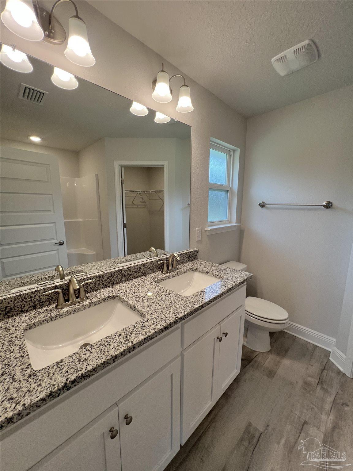 904 Rustling Pine Road, Unit 22B Cantonment, FL 32533 - Photo 8 of 10 a bathroom with a granite countertop sink a toilet and a mirror