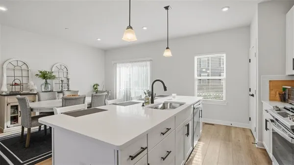 a kitchen with stainless steel appliances stove a sink and white cabinets with wooden floor