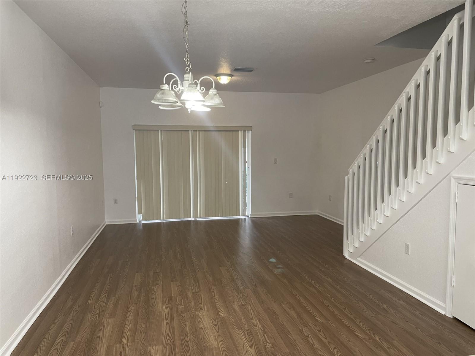 8831 South Isles Circle, Unit 8831 Tamarac, FL 33321 - Photo 12 of 22 a view of an empty room with wooden floor and a chandelier