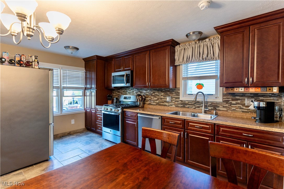 1400 East Miner Road Cleveland, OH 44124 - Photo 8 of 25 Kitchen with pendant lighting, sink, a chandelier, appliances with stainless steel finishes, and decorative backsplash