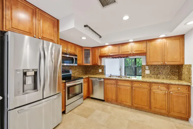 a kitchen with stainless steel appliances granite countertop a refrigerator a stove and a sink with wooden floors