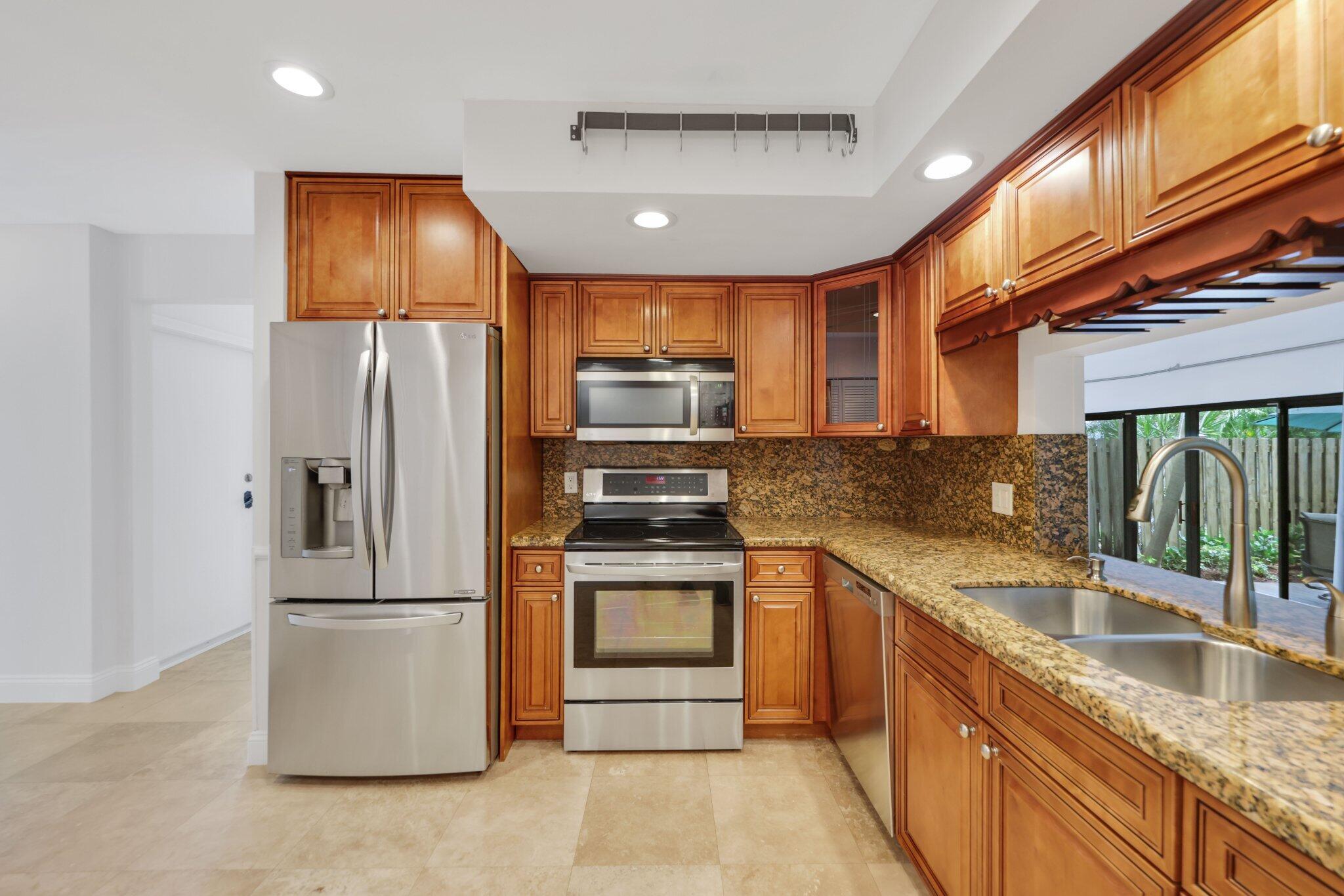 361 West Camino Real, Unit 9 Boca Raton, FL 33432 - Photo 14 of 37 a kitchen with stainless steel appliances granite countertop a refrigerator a stove and a sink with wooden floors