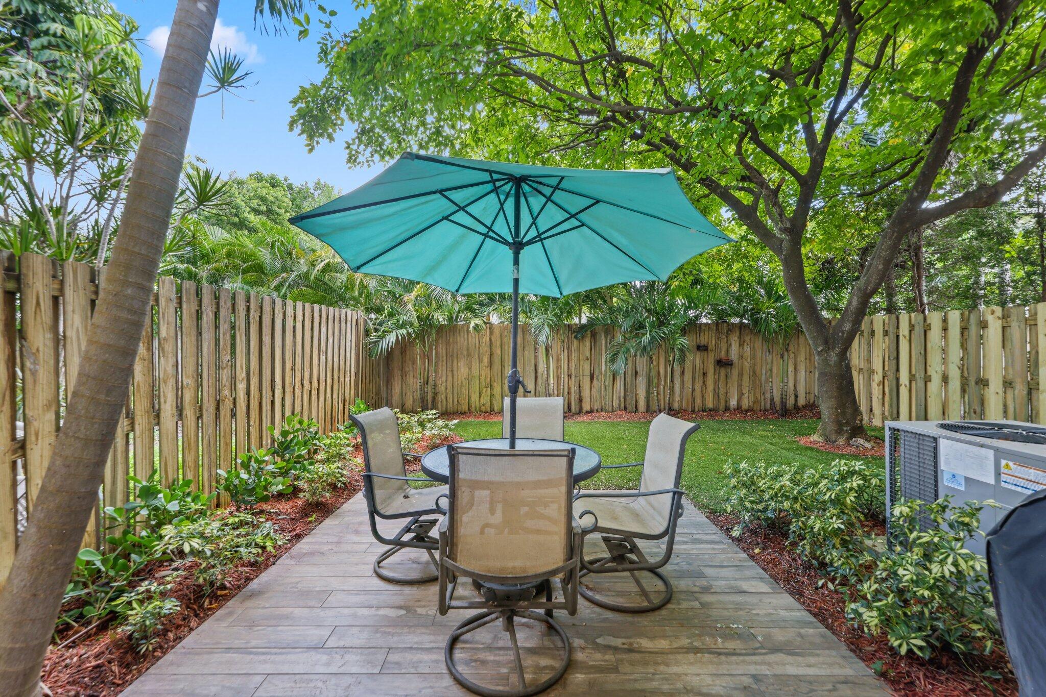 361 West Camino Real, Unit 9 Boca Raton, FL 33432 - Photo 26 of 37 a view of a table and chairs under an umbrella in backyard