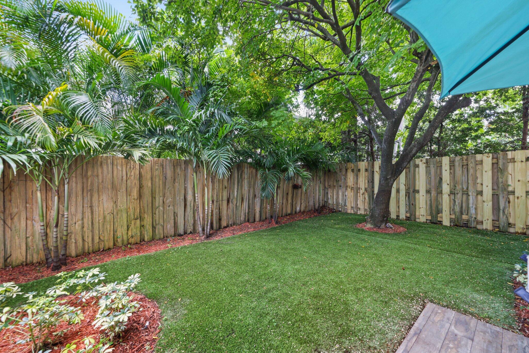 361 West Camino Real, Unit 9 Boca Raton, FL 33432 - Photo 27 of 37 a view of a backyard with large trees and wooden fence