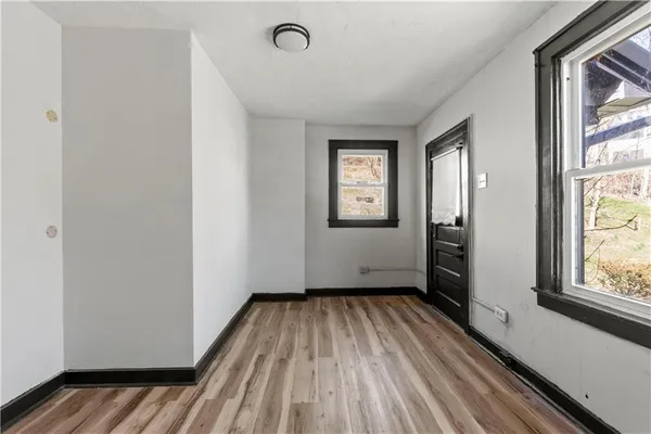 a view of an empty room with a window and wooden floor