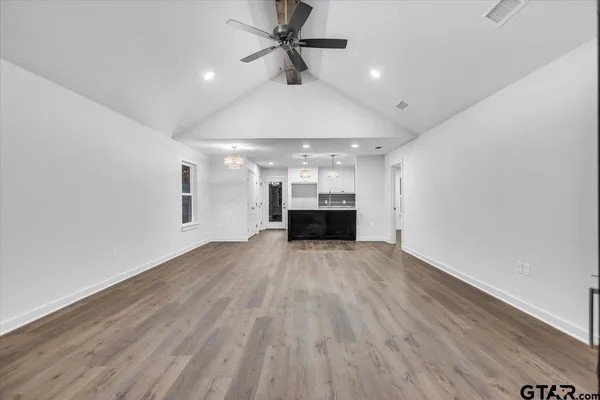 a view of empty room with wooden floor and ceiling fan