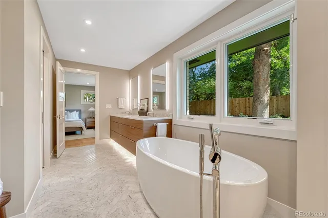 a bathroom with a tub a sink and a large window