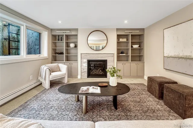 a living room with furniture a rug a fireplace and a window