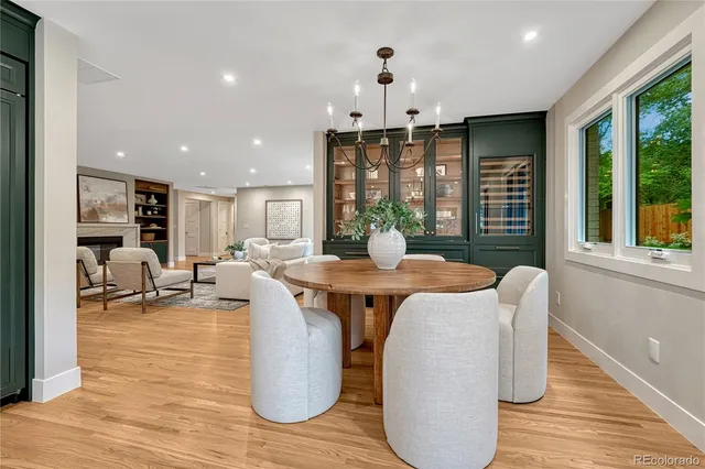 a dining room with wooden floor a chandelier a glass table and chairs