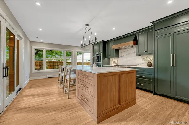 a kitchen with stainless steel appliances kitchen island granite countertop a refrigerator a stove a sink dishwasher and a dining table with wooden floor