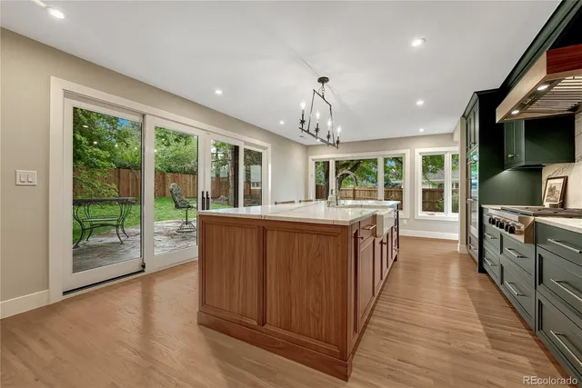 a open kitchen with kitchen island granite countertop a large window a sink and stainless steel appliances