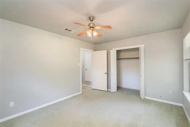 an empty room with closet and a chandelier fan