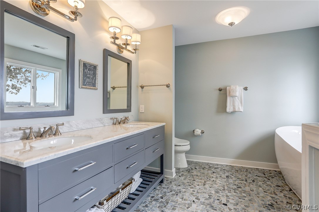 5149 Wakema Road West Point, VA 23181 - Photo 33 of 47 a bathroom with a double vanity sink a toilet and a mirror