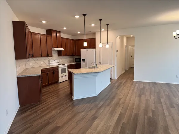 a large kitchen with granite countertop a large counter top space a sink stainless steel appliances and cabinets