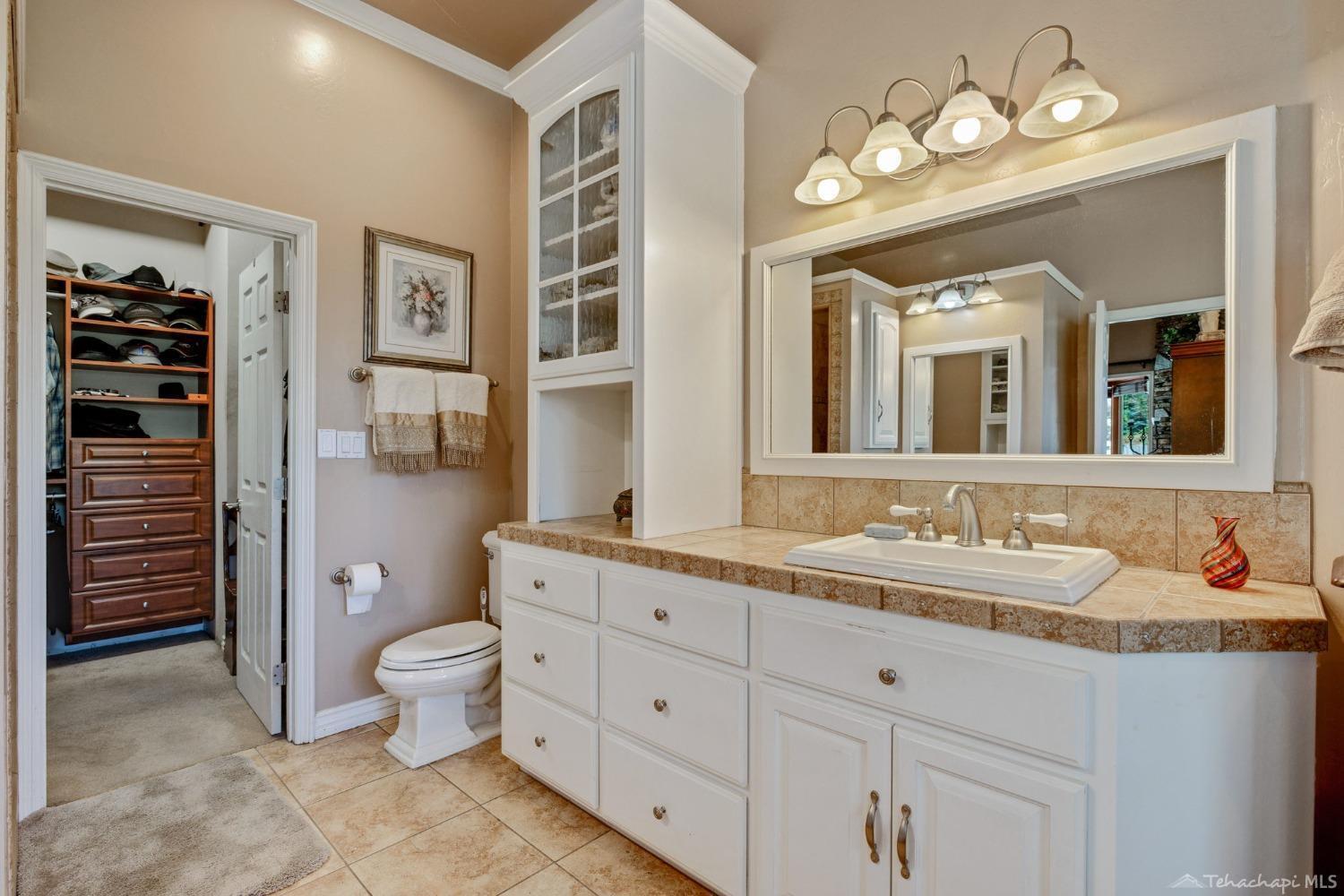 24500 Heather Court Tehachapi, CA 93561 - Photo 27 of 60 a spacious bathroom with a granite countertop double vanity sink a toilet and a mirror