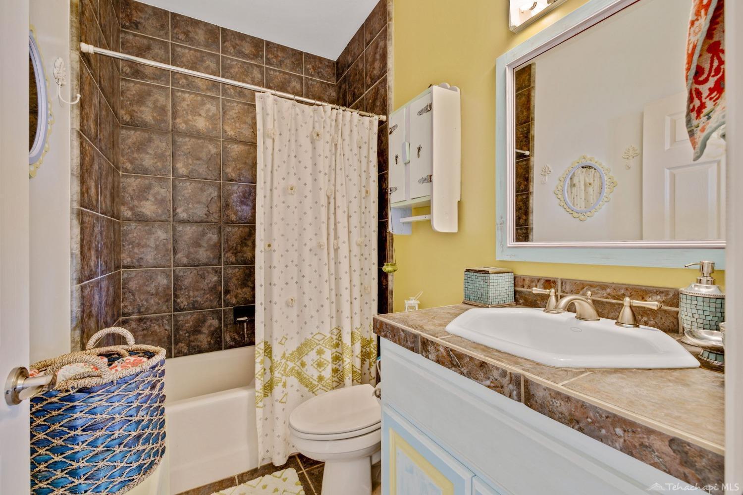 24500 Heather Court Tehachapi, CA 93561 - Photo 35 of 60 a bathroom with a granite countertop bathtub sink vanity mirror and toilet