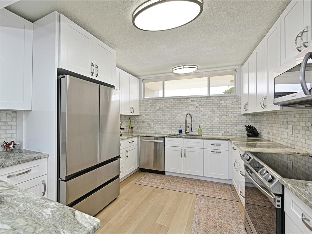 100 Sands Point Road, Unit 225 Longboat Key, FL 34228 - Photo 13 of 32 a kitchen with stainless steel appliances granite countertop a sink stove refrigerator and cabinets