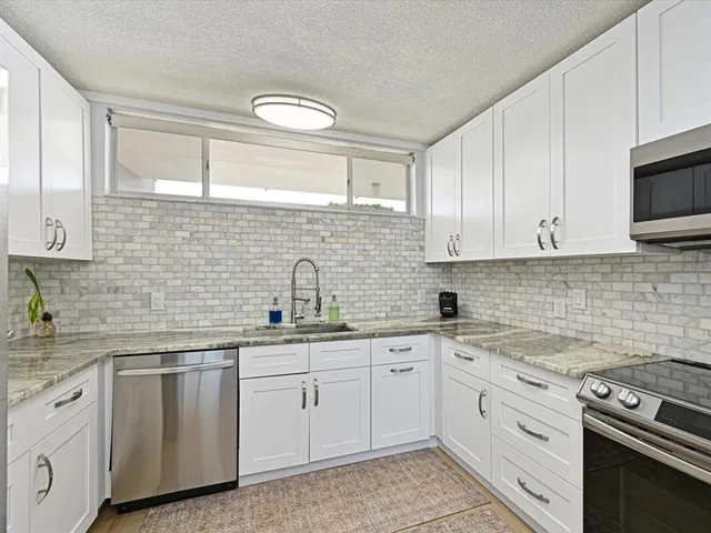 a kitchen with white cabinets appliances and a sink