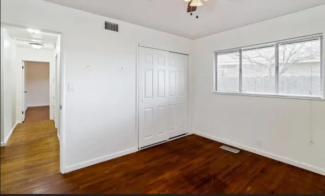 a view of empty room with wooden floor and fan