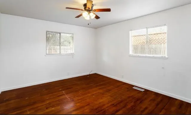 a view of an empty room with wooden floor and a window