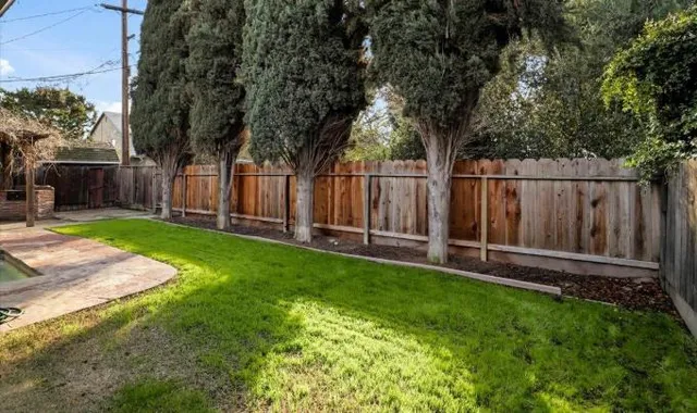 a view of backyard with wooden fence and large trees