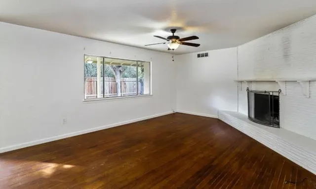 a view of an empty room with a fireplace and a window