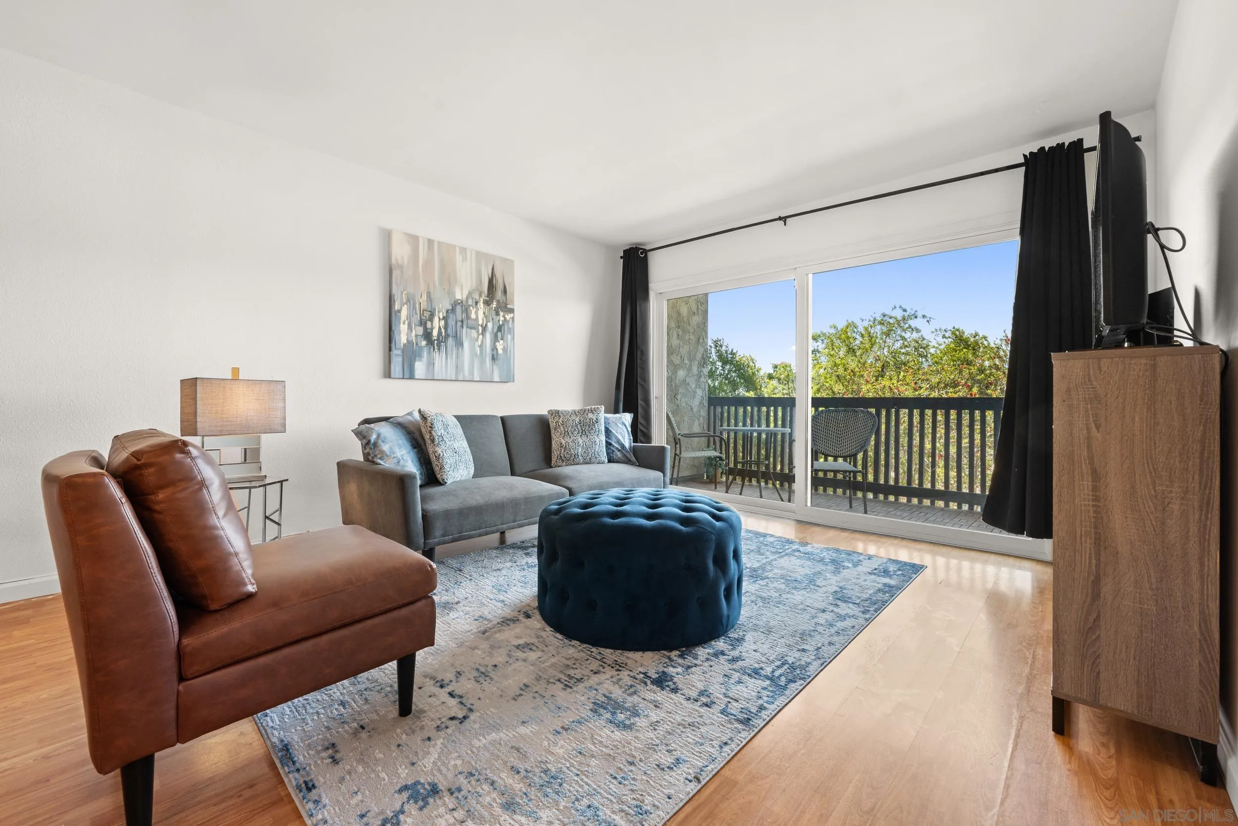 6202 Friars Road, Unit 215 San Diego, CA 92108 - Photo 6 of 18 a living room with furniture a flat screen tv and a floor to ceiling window