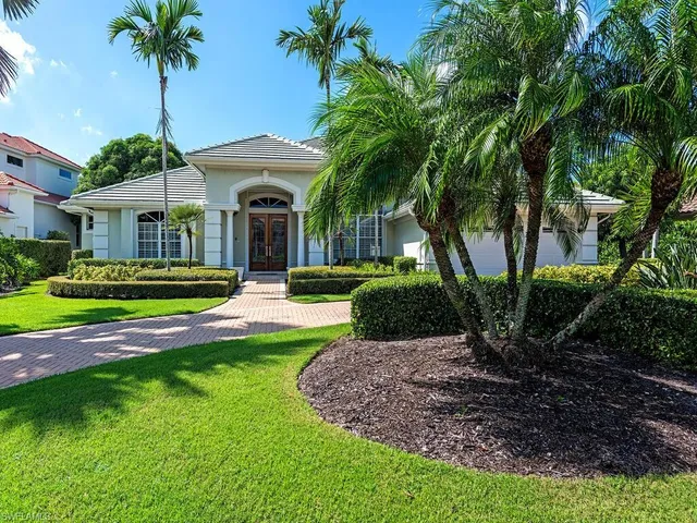 front view of a house with a yard and palm trees