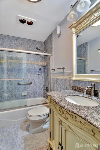 a bathroom with a granite countertop toilet a sink and a mirror