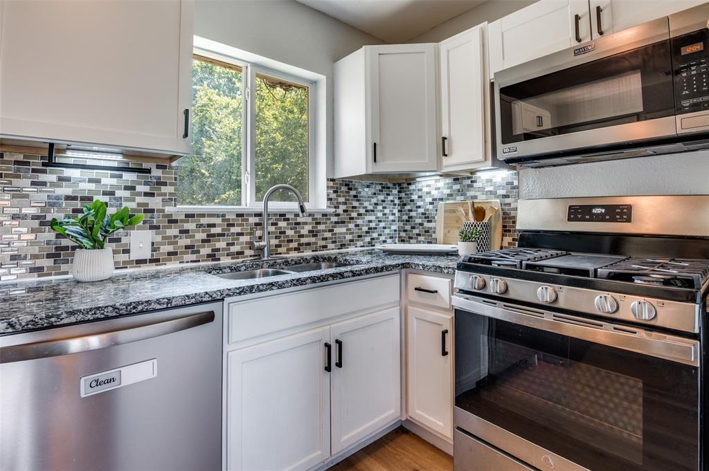406 Freeman Street Mesquite, TX 75149 - Photo 11 of 22 a kitchen with stainless steel appliances granite countertop a sink a stove a microwave and wooden cabinets