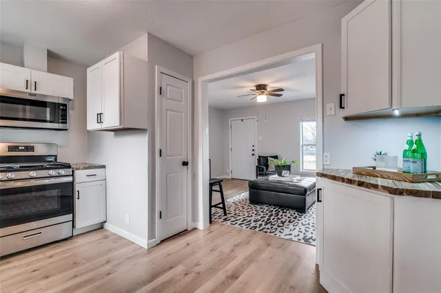 a kitchen with stainless steel appliances kitchen island granite countertop a refrigerator stove top oven and sink with wooden floor