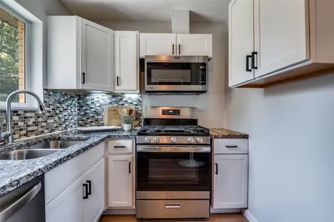 a kitchen with stainless steel appliances granite countertop a sink a stove a microwave and wooden cabinets