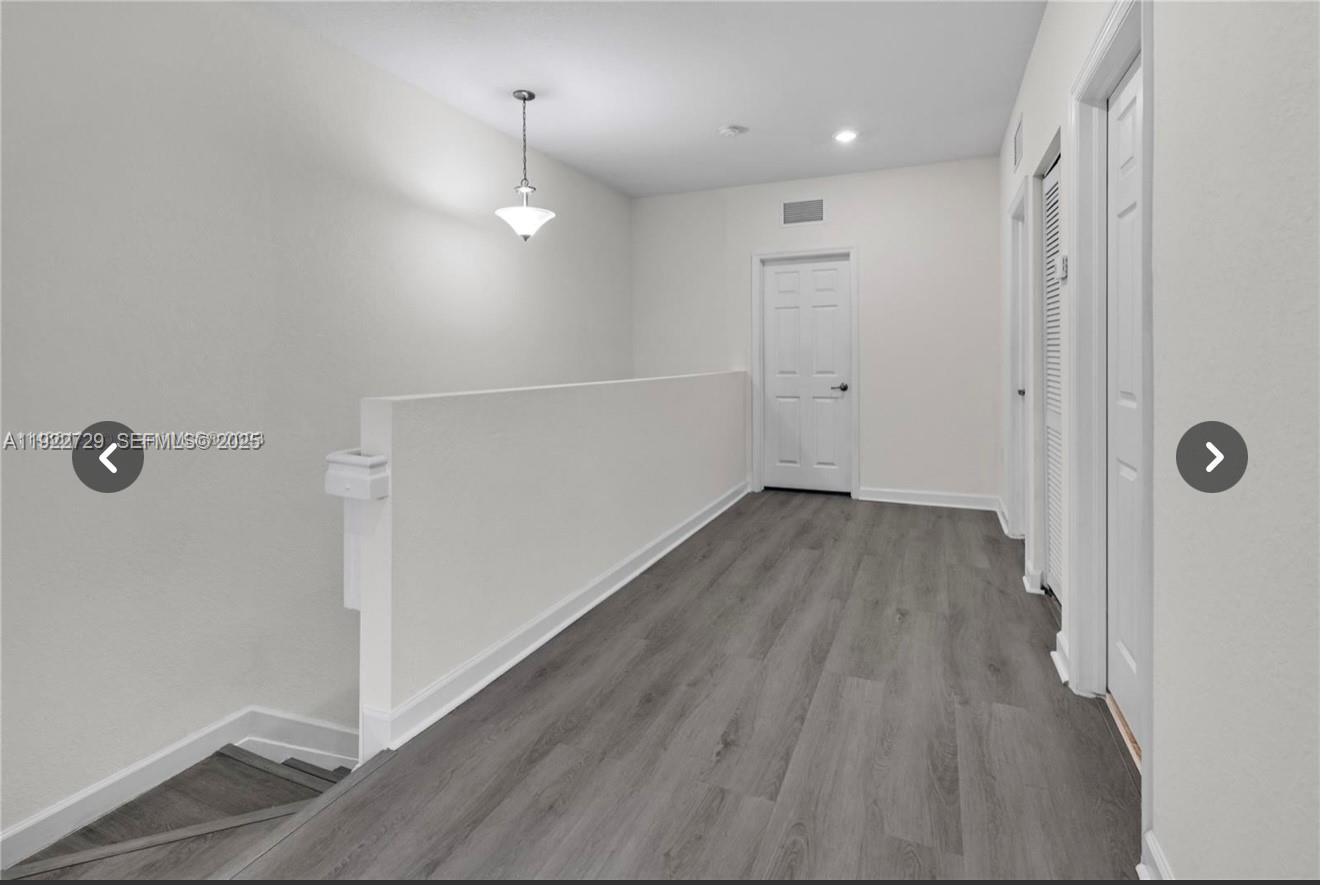 10091 West 35th Lane, Unit 10091 Hialeah, FL 33018 - Photo 14 of 32 a view of a room with wooden floor and white walls