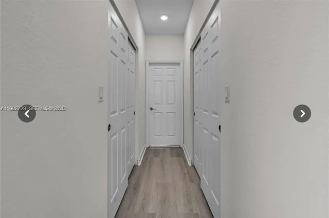 a view of a hallway with wooden floor and a shower